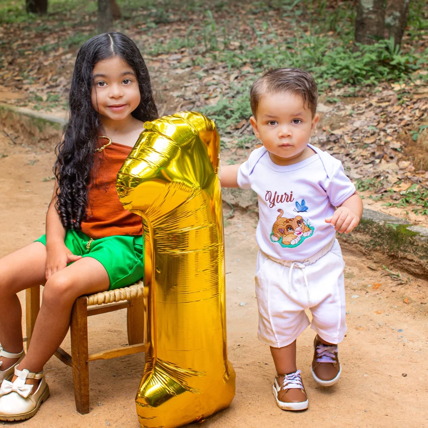Ensaio infantil comemoração de um ano com balão dourado na natureza e crianças sorrindo