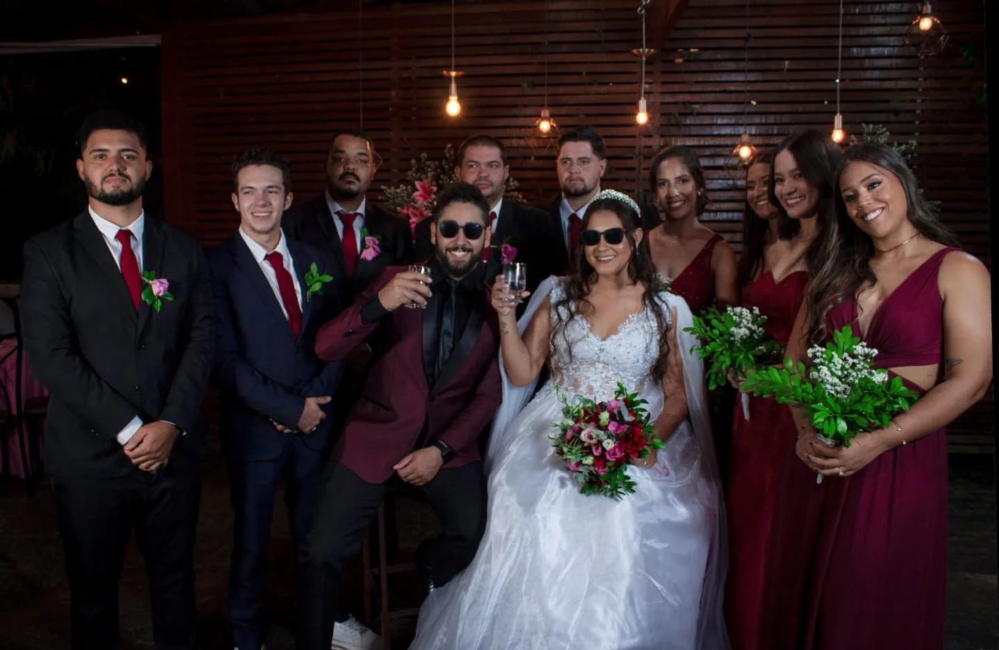 Registro emocionante de casamento com brinde da noiva de vestido branco e noivo com padrinhos e madrinhas em ambiente aconchegante